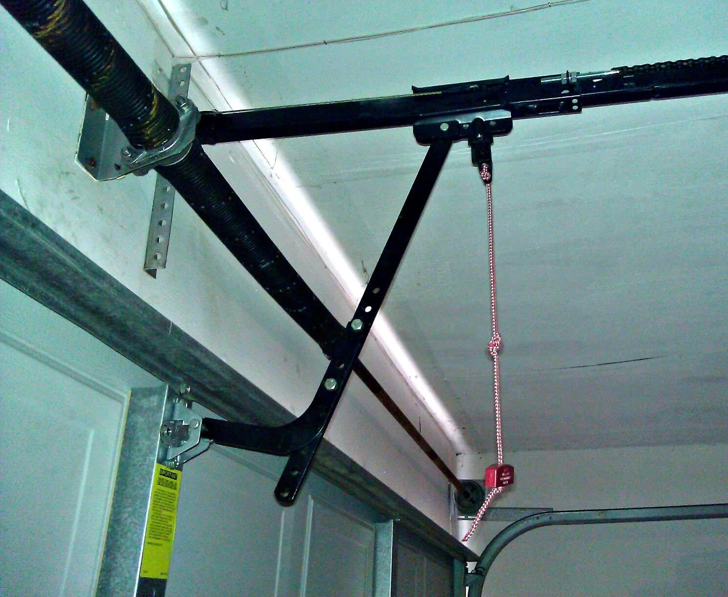 High tension garage door spring mechanism inside a residential garage tracking configuration