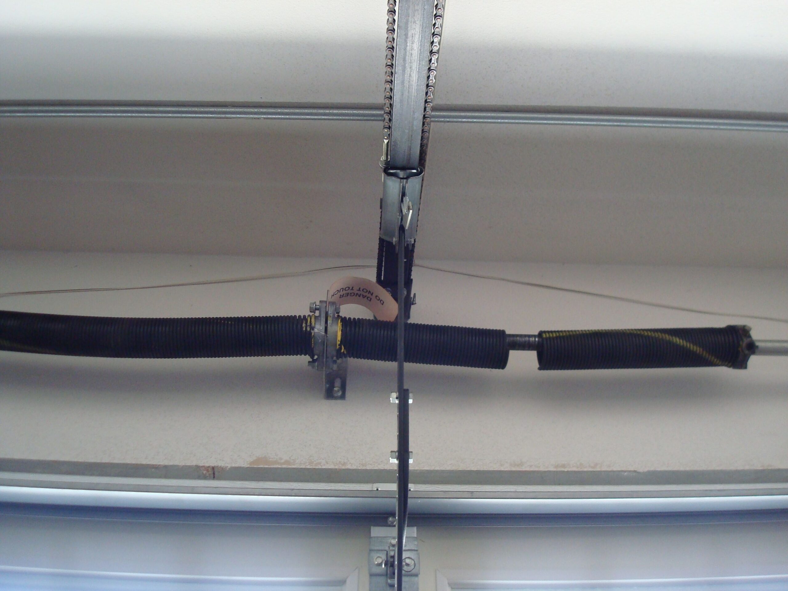 Technician repairing a garage door torsion spring